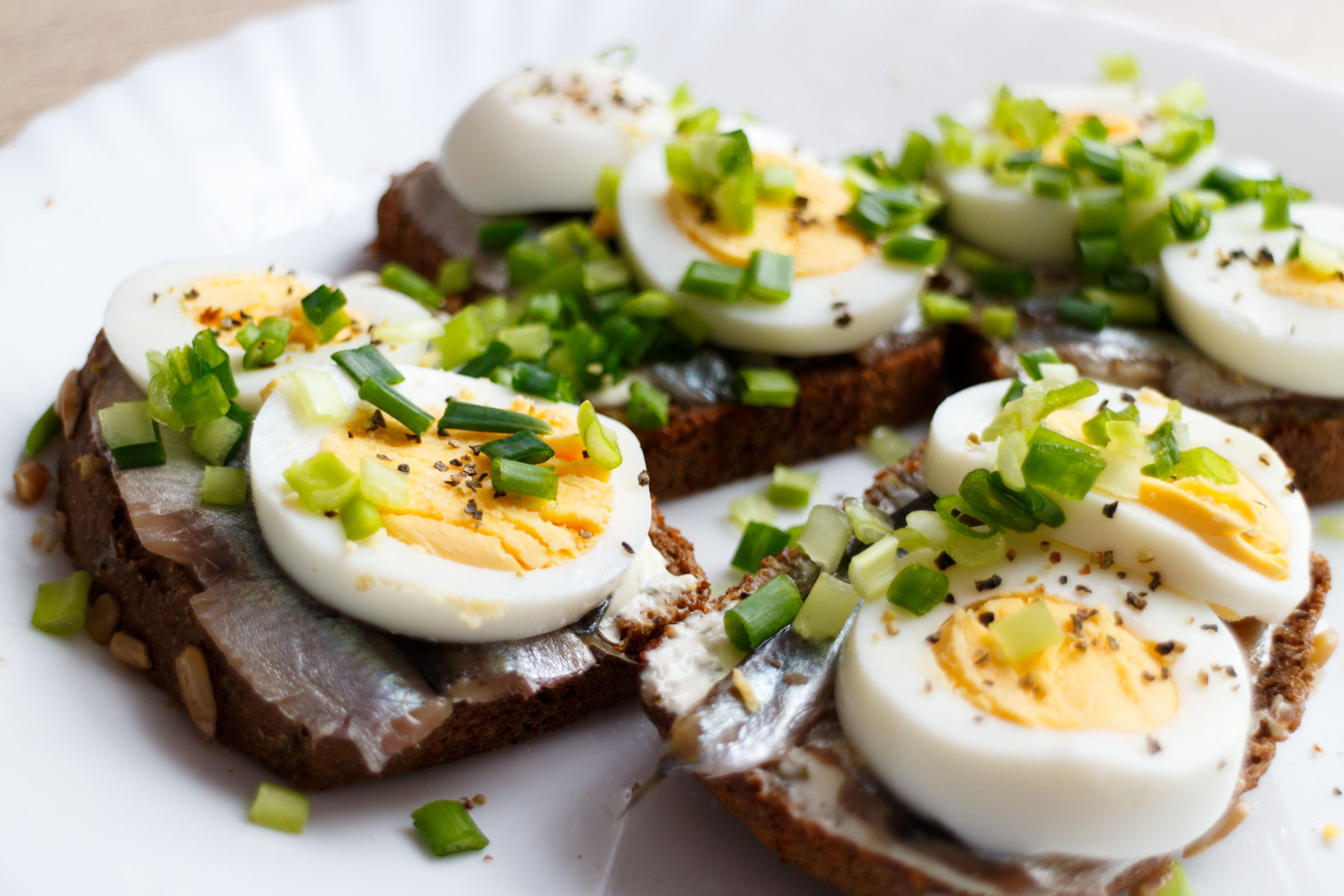 A plate of boiled eggs on dark brown rye bread, a traditional dish in Estonia.