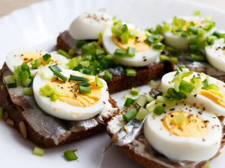 A plate of boiled eggs on dark brown rye bread, a traditional dish in Estonia.