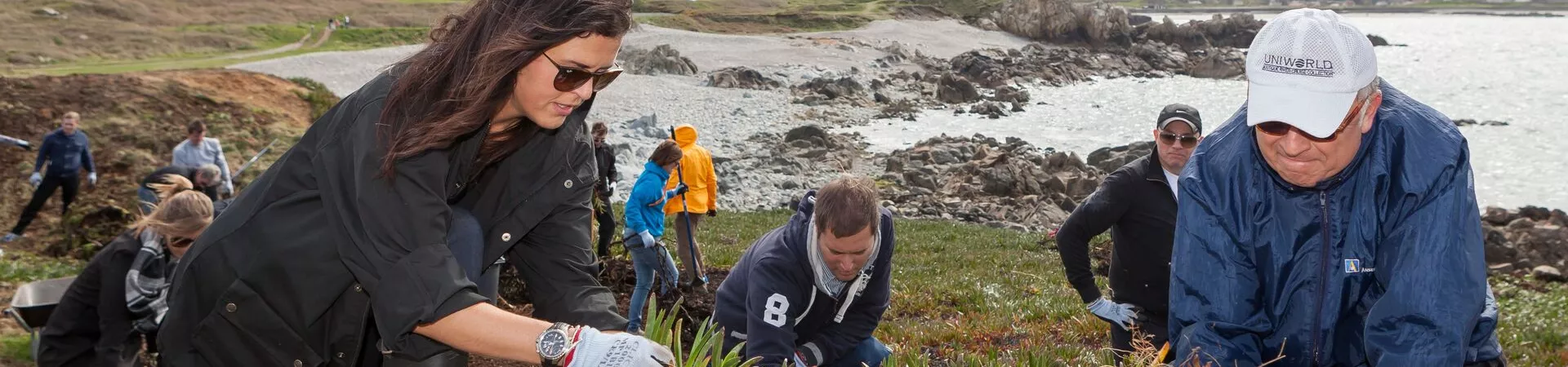 Shannon, Chief Sustainability Officer, planting with a group of people by the sea