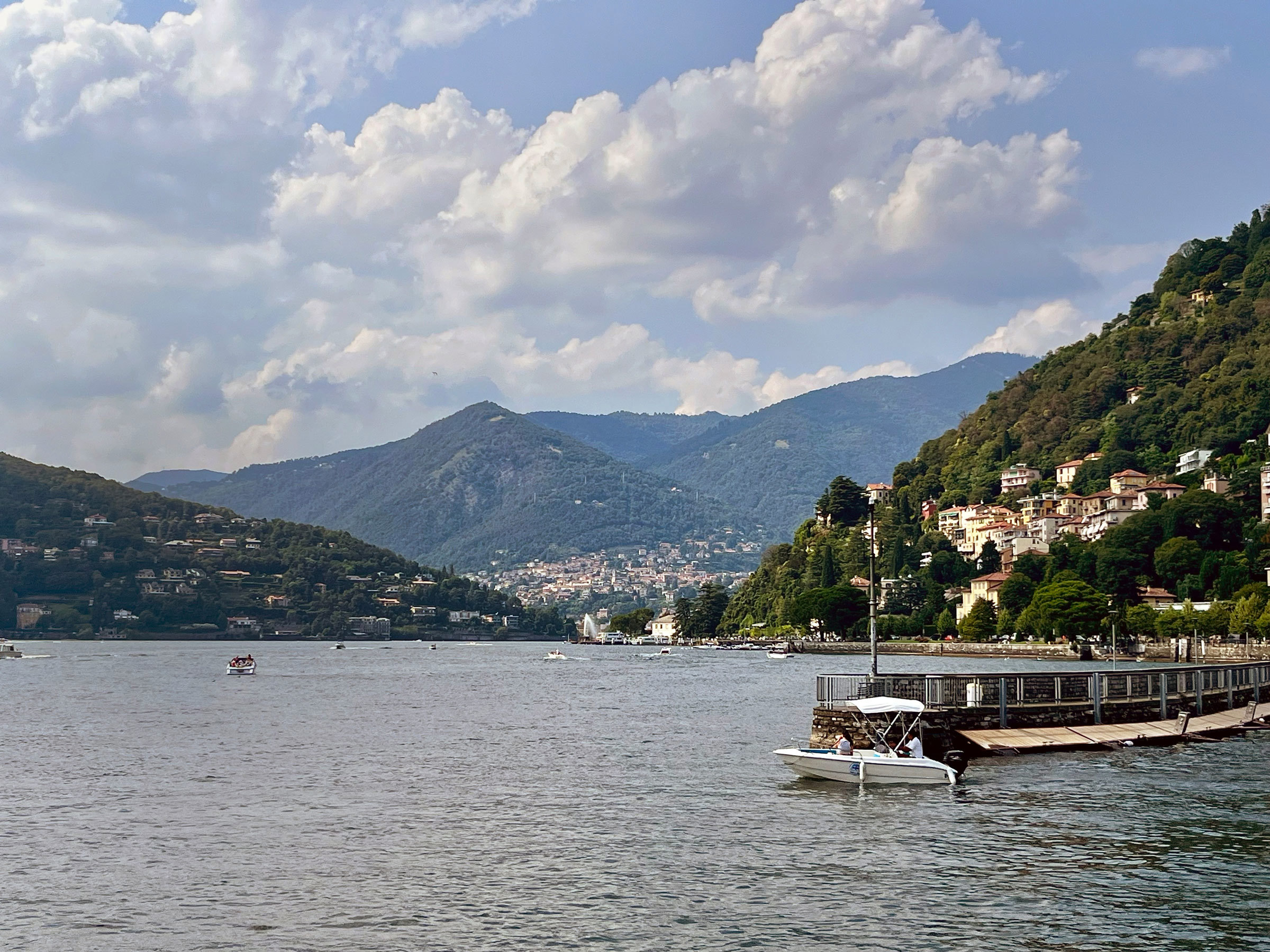 Scenic lakeside view with boats and houses under cloudy sky in Lake Como, Italy
