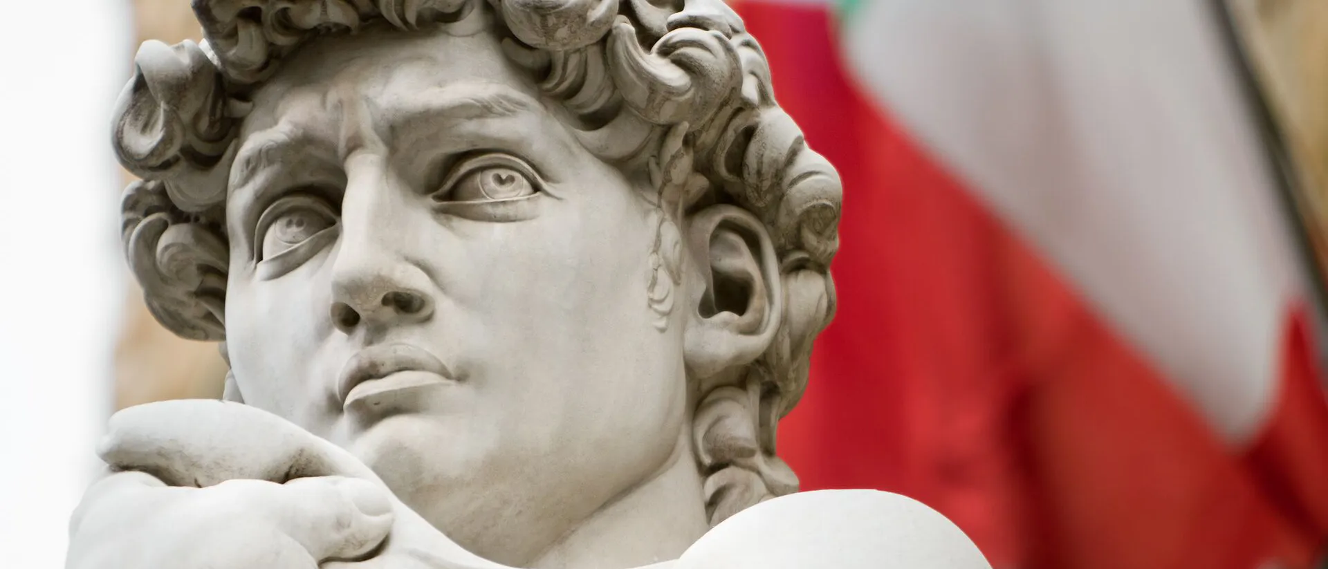 Sculpture of Michaelangelo with Italy flag in the background