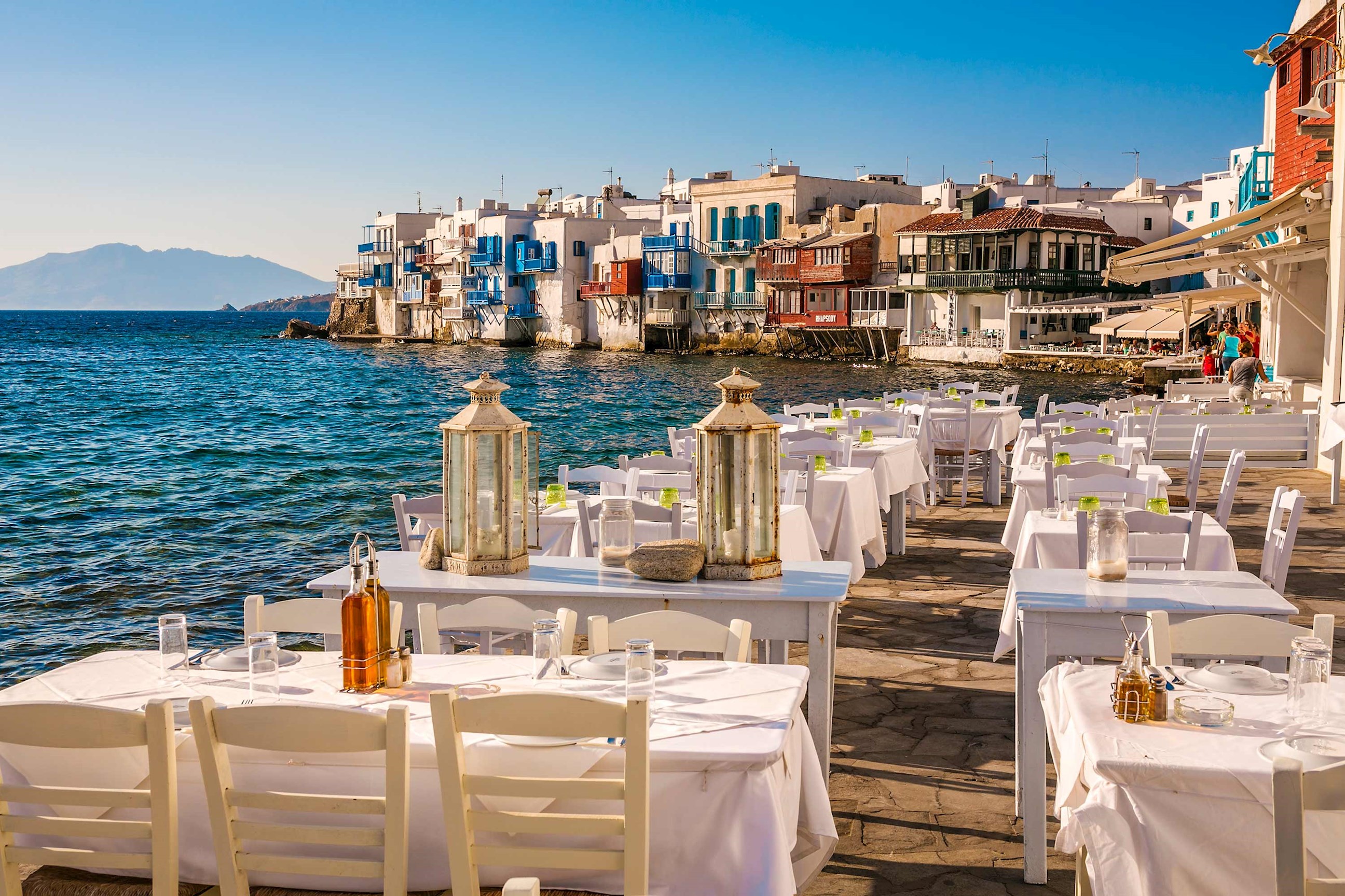 Seaside restaurant with white tables overlooking Little Venice in Mykonos, Greece