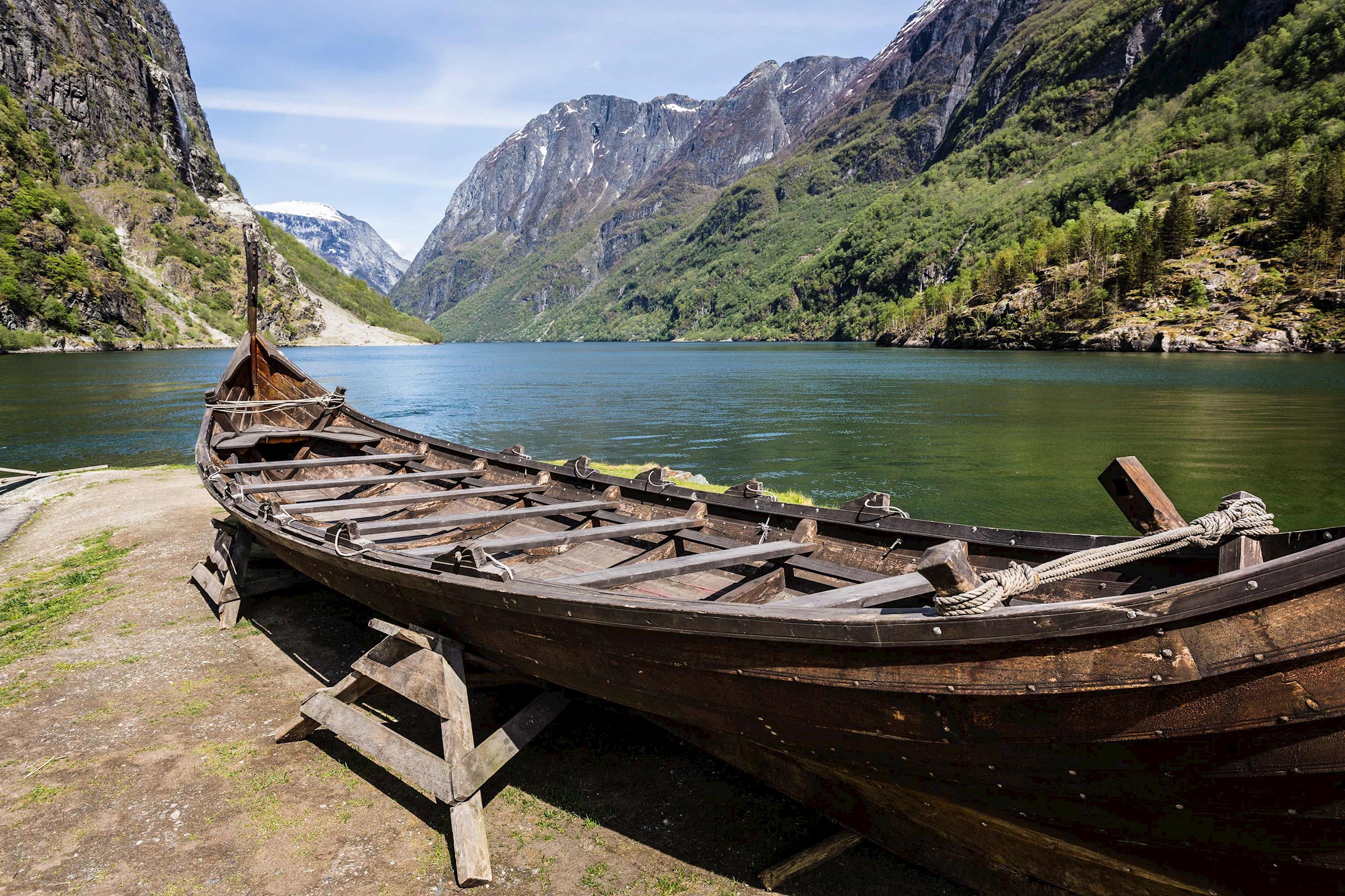 Wooden boat on shore with mountains behind in Sognefjord, Norway
