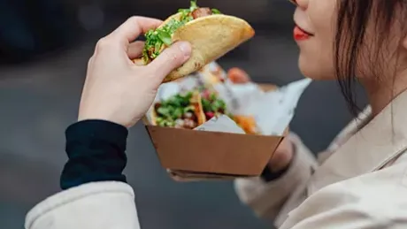 A woman is eating a taco and filled with salad in Food Cart Tour In New York Usa