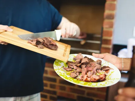Chef scraping Brazilian BBQ onto a plate in Brazil