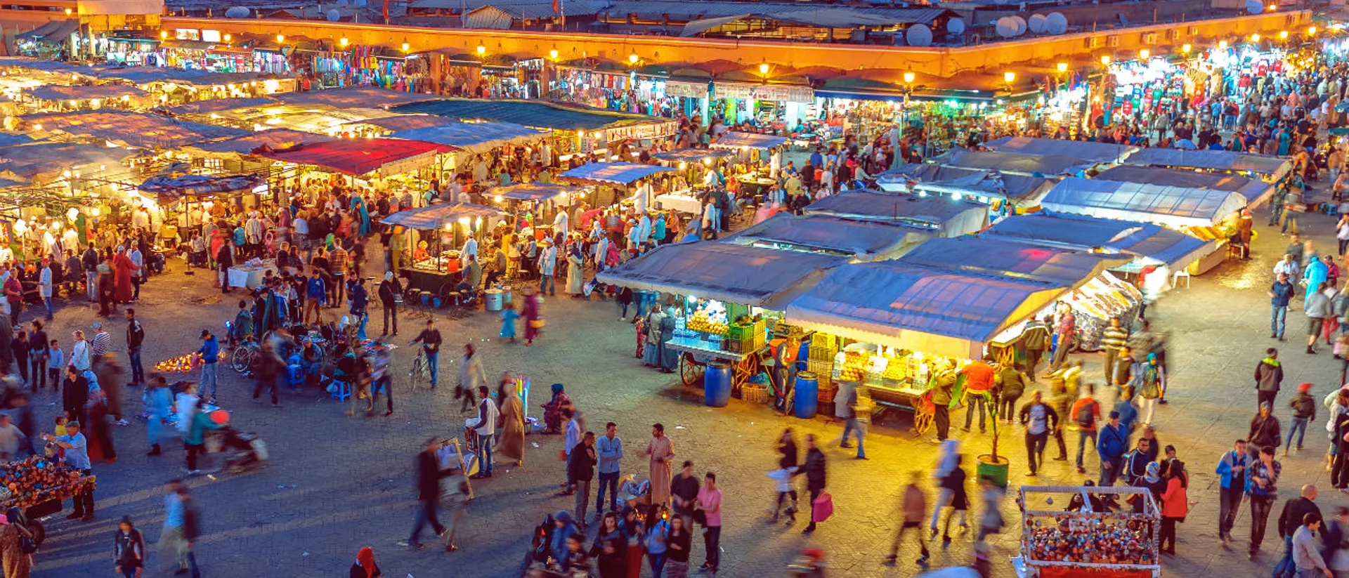 A crowd of people walking around a souk or market at night in Morocco