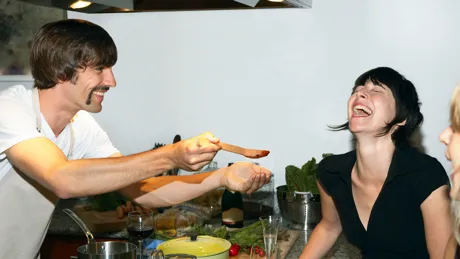 Lady smiling while a chef holds out a spoon for her to try