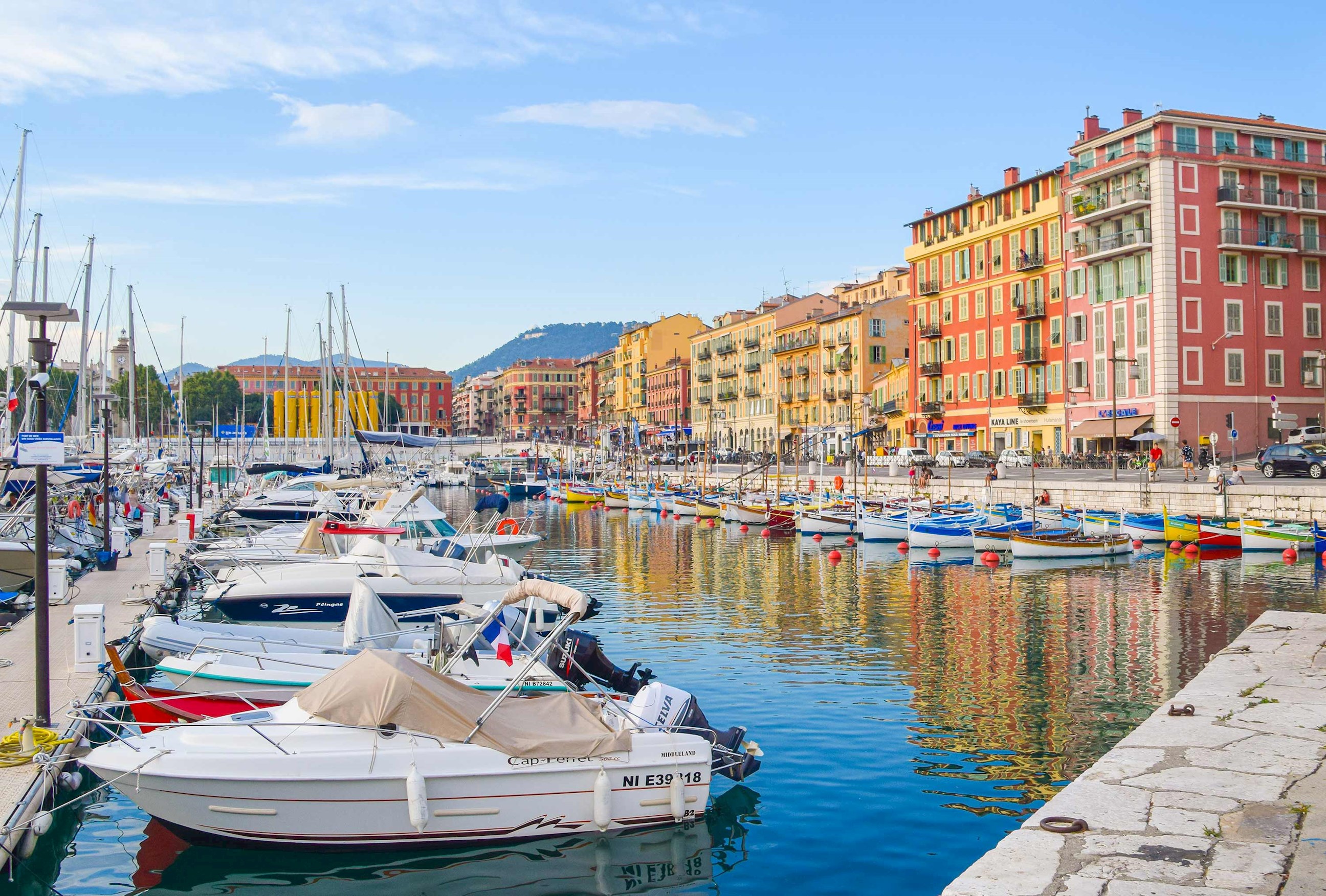Boats docked in Nice marina with colourful waterfront buildings 