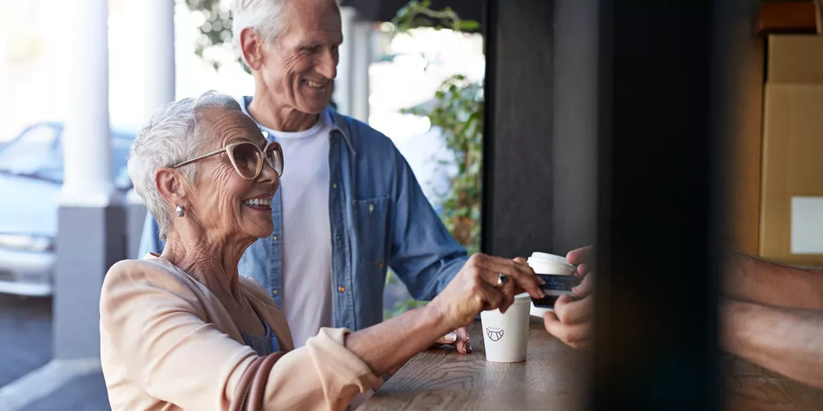 Senior Couple Ordering Coffee To Go At Street Bakery