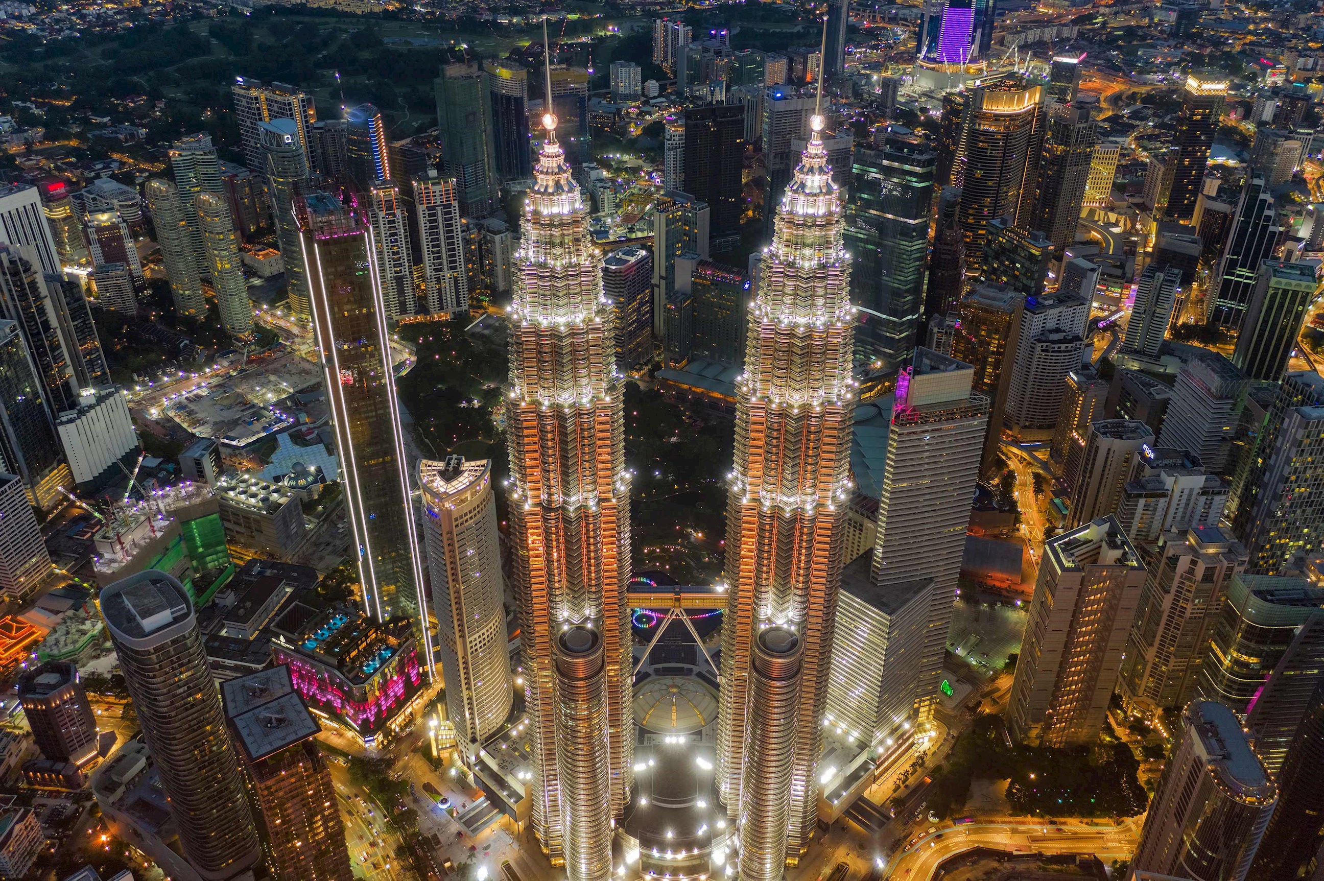 Aerial night view of Petronas Twin Towers surrounded by Kuala Lumpur skyline in Malaysia