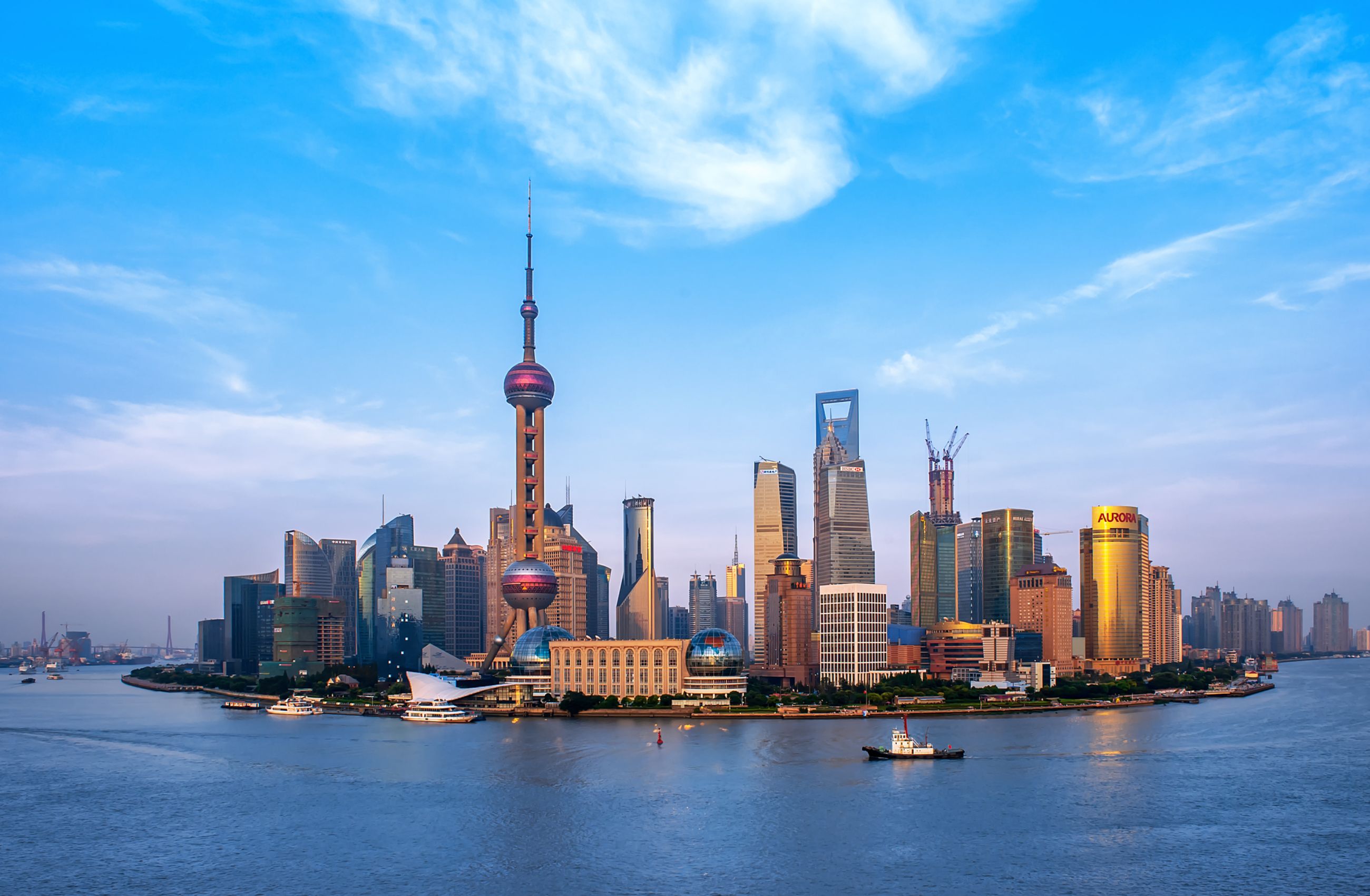 A skyline of Shanghai, made up of skyscrapers and the striking Pearl TV Tower with a tall spire.