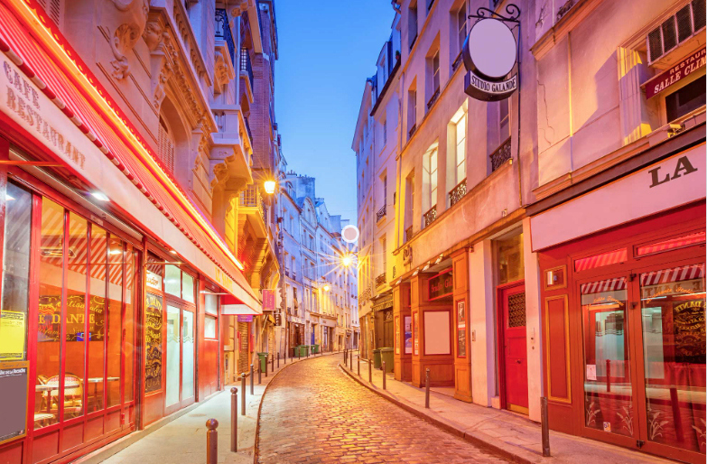 External view of a narrow cobblestone street illuminated by vibrant neon lights in Paris, France