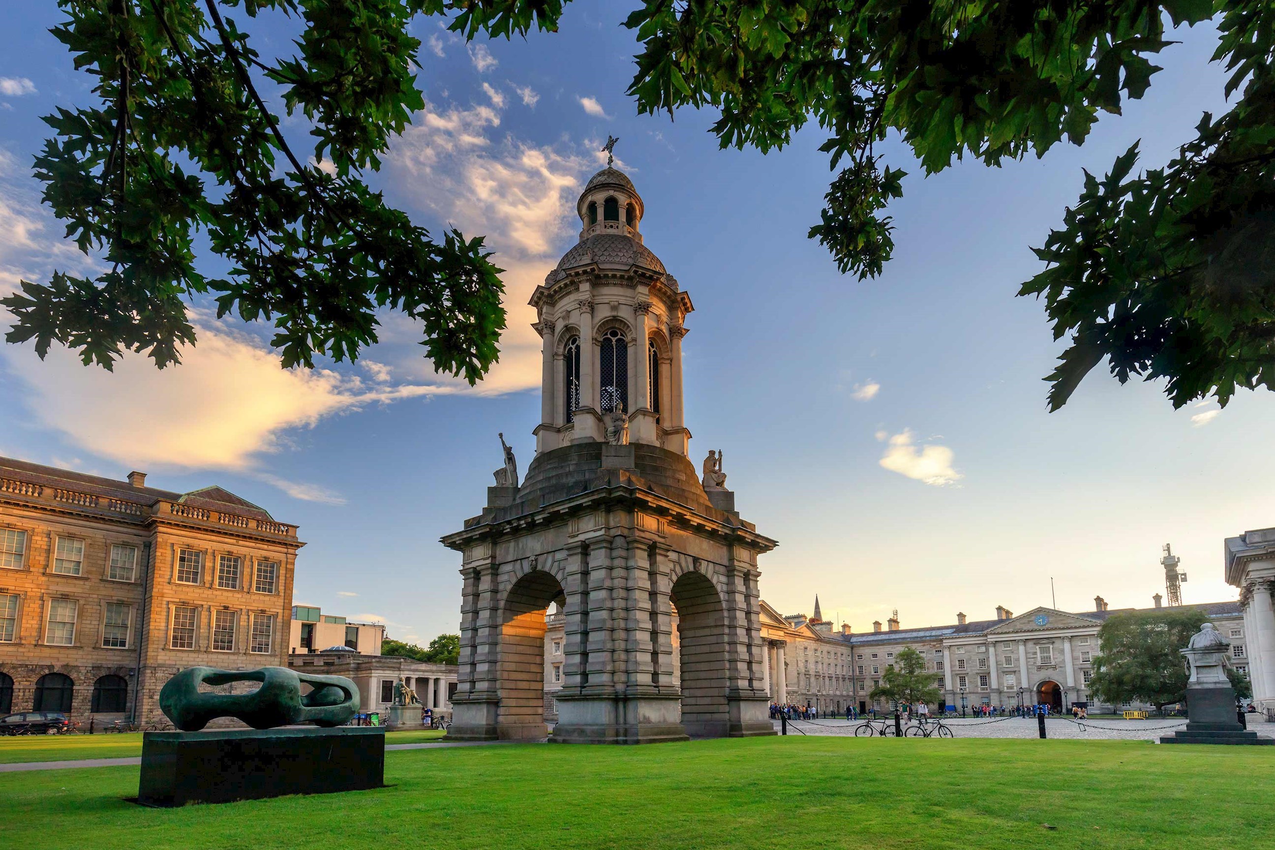 Historic tower framed by leafy branches under an evening sky in Dublin, Ireland