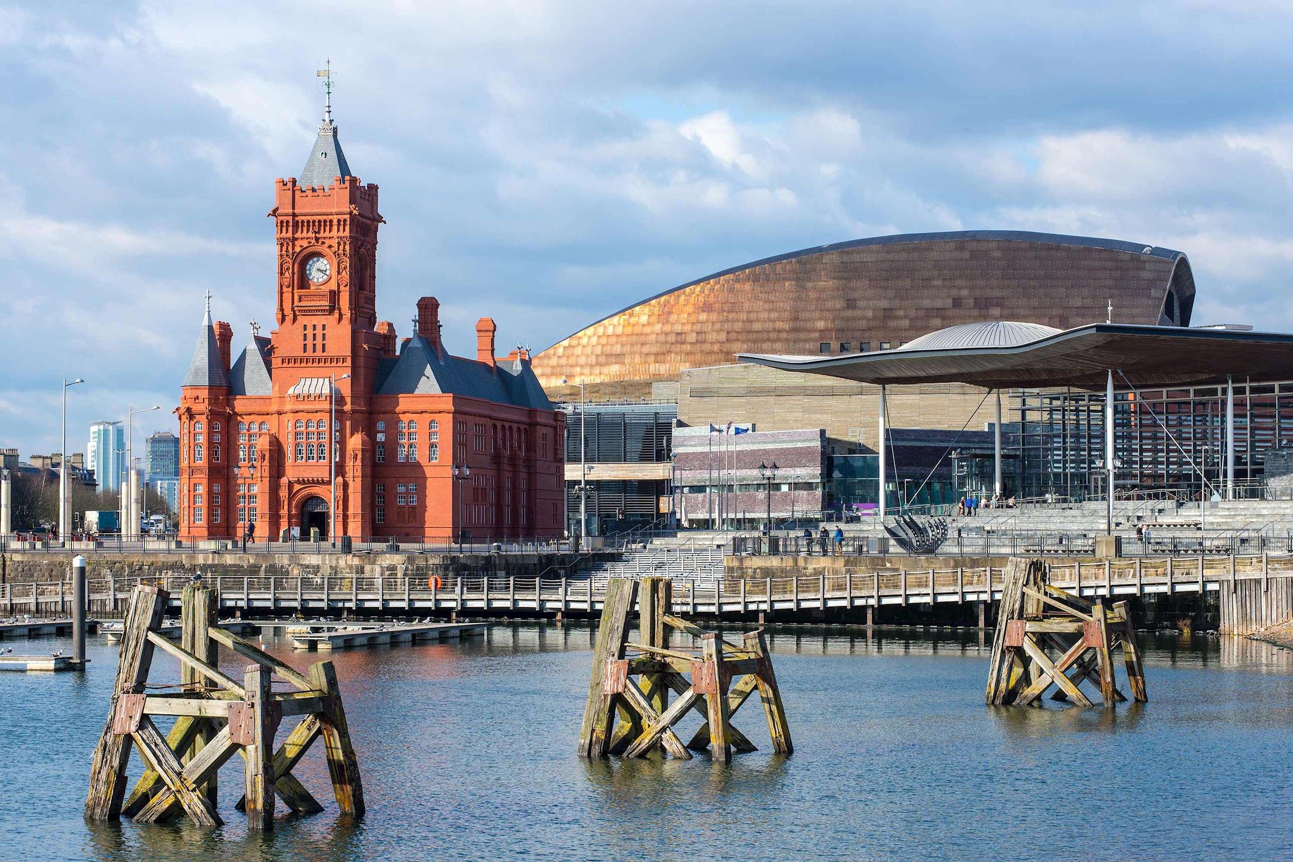 Historic red building beside modern curved building in Cardiff, Wales
