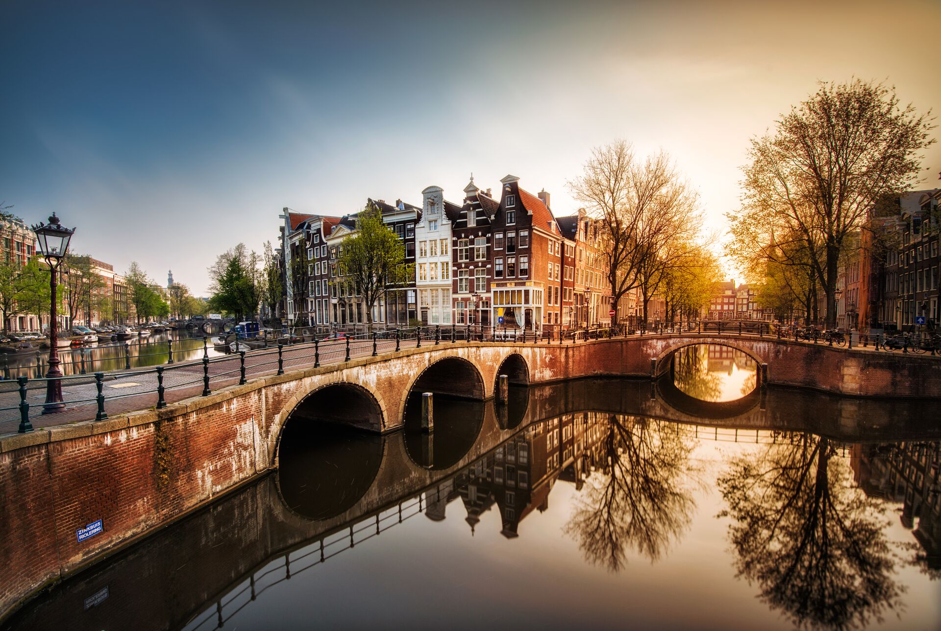 Gentle Dawn sunlight illuminates the Amsterdam canal and surrounding buildings