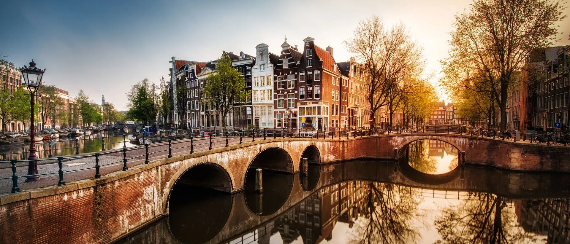 Gentle Dawn sunlight illuminates the Amsterdam canal and surrounding buildings