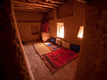 Simple traditional room with clay walls and red carpet, Bhalil, Fes Meknes, Morocco