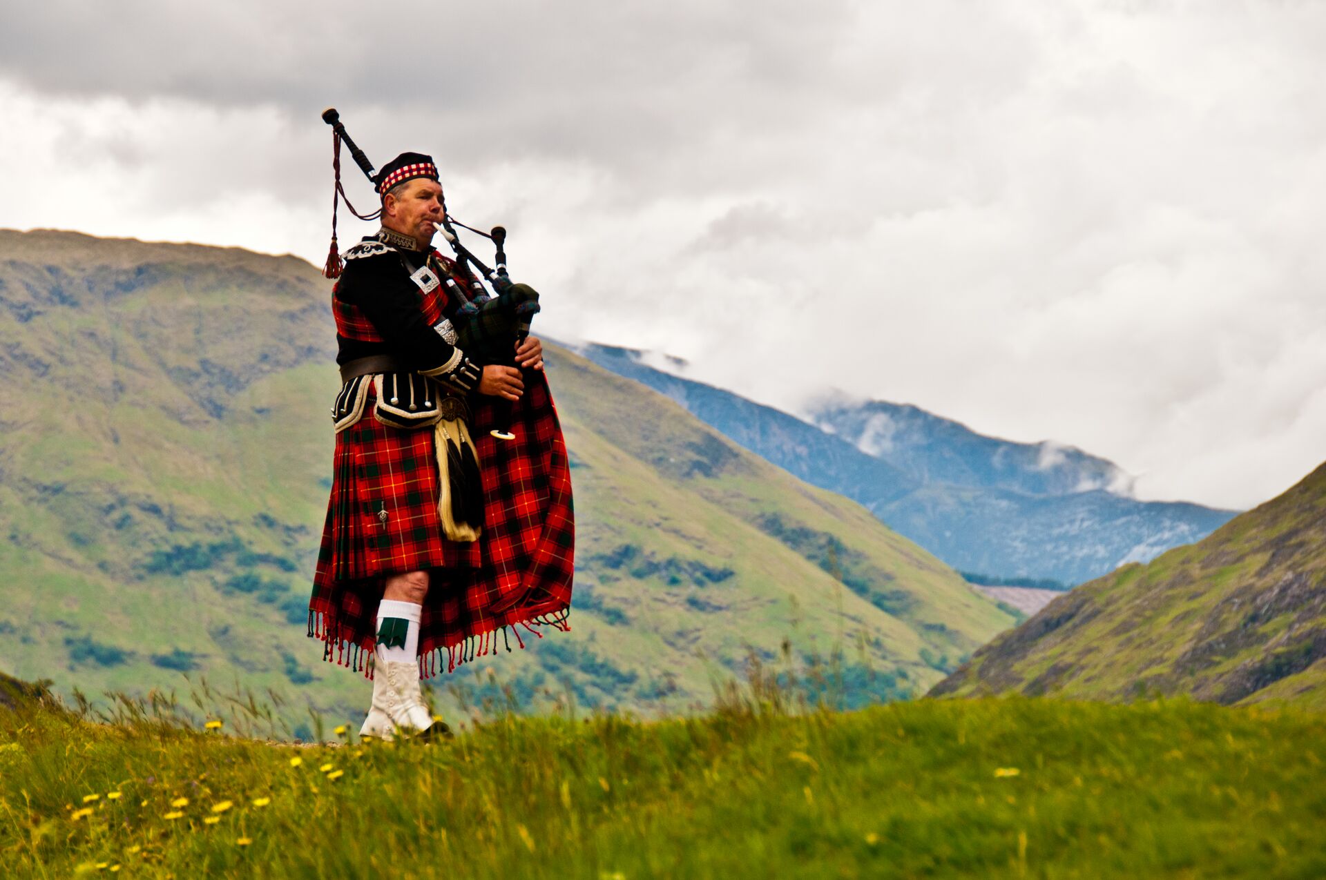 Highland Bagpiper In Kilt in mountainside, Scotland
