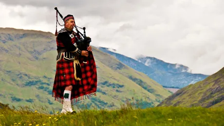 Highland Bagpiper In Kilt in mountainside, Scotland