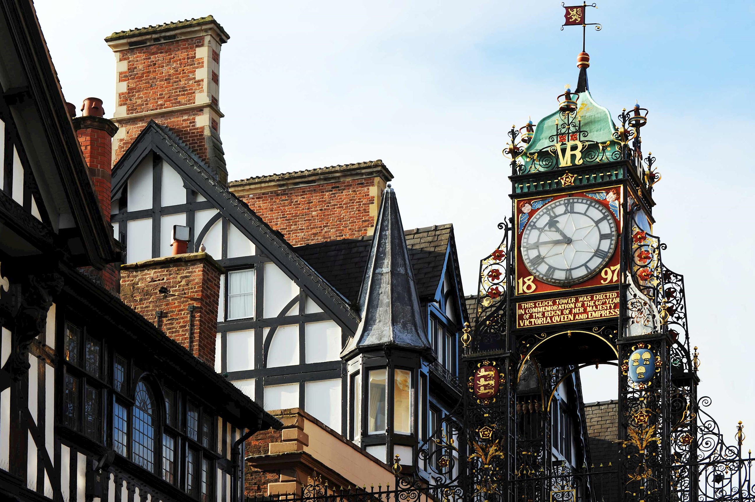 Decorative clock tower and traditional architecture under clear blue sky in Chester, England