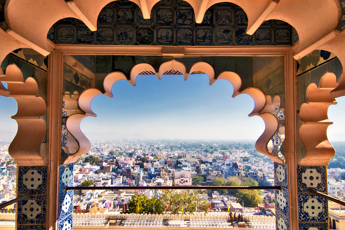 City view of Udaipur framed by arch with blue tile patterns at City Palace, India