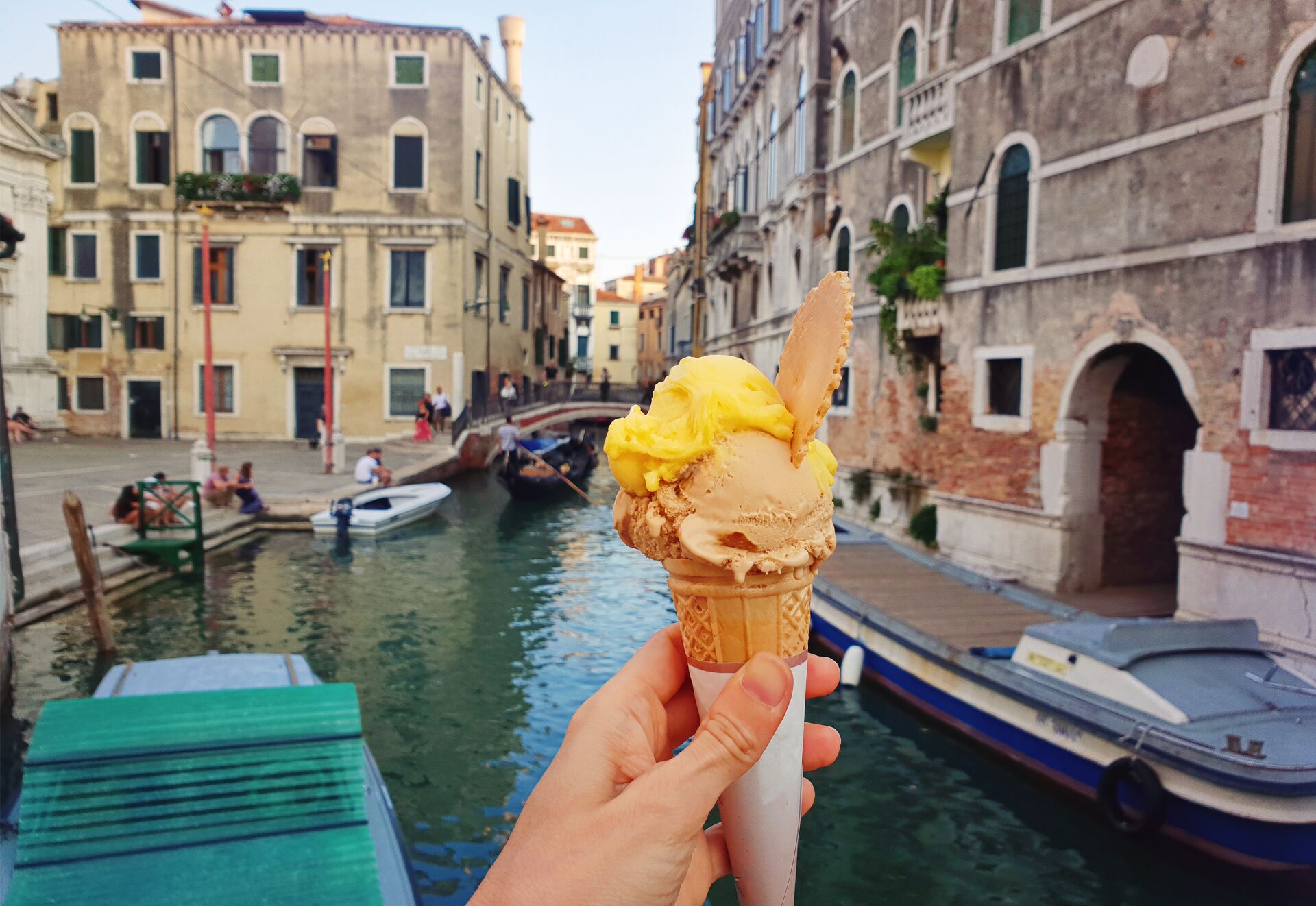 Hand holding gelato in front of Venice's canals
