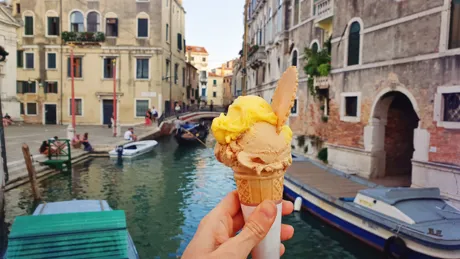 Hand holding gelato in front of Venice's canals