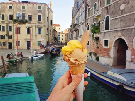 Hand holding gelato in front of Venice's canals