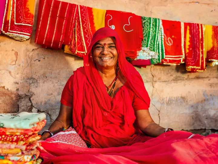 Indian Woman sat on floor amidst the colourful fabrics she's selling in India