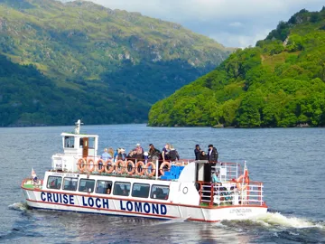 Cruise Loch Lomond boat sailing on calm water with green hills in background