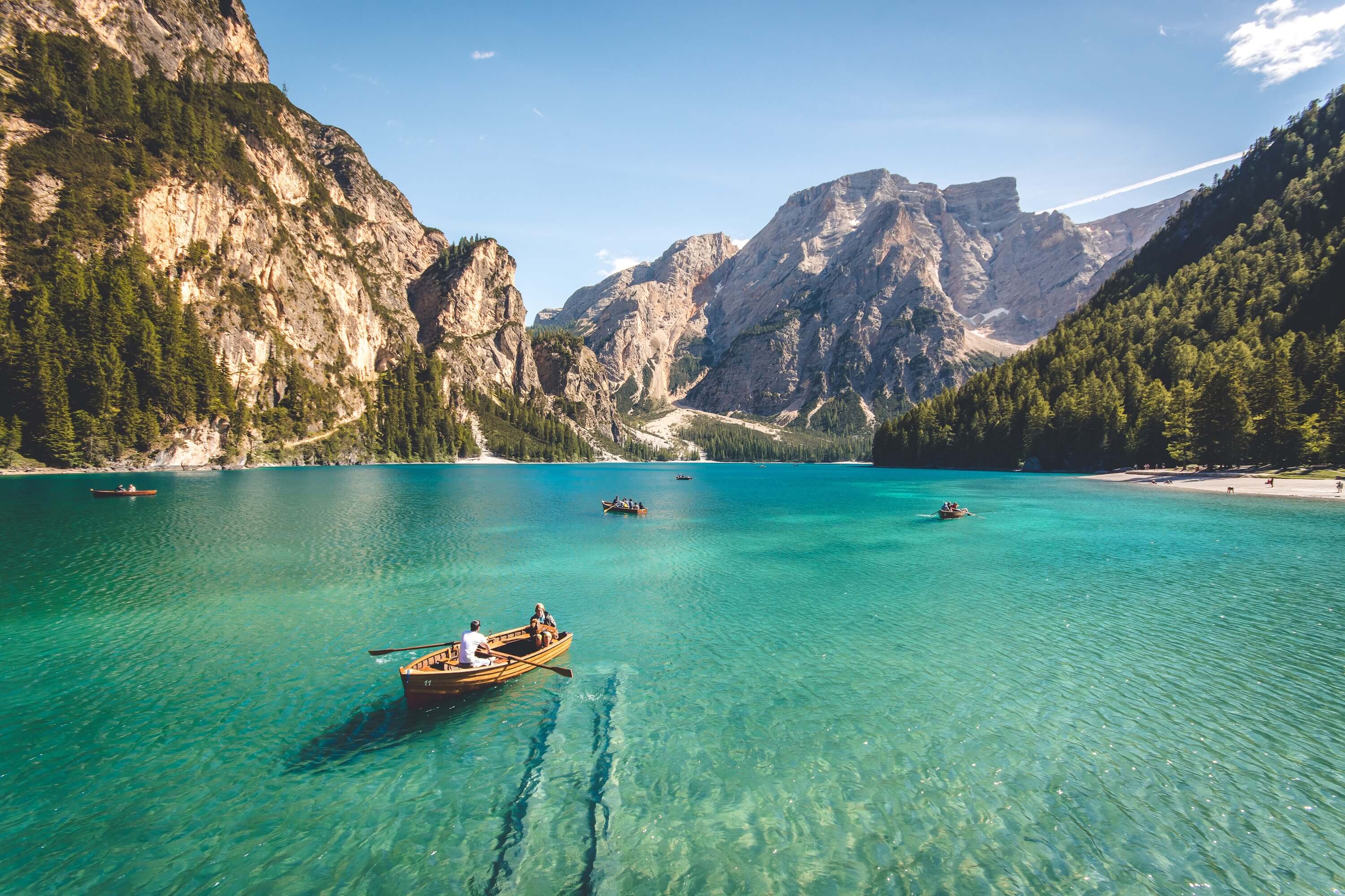 Small boats on a lake with clear water, surrounded by mountains.