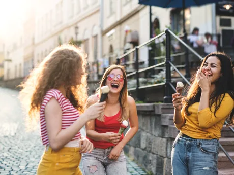 Three Cheerful Female Teenager Friends With Ice Cream Standing On The Street, Laughing