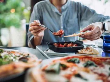 Close view of a dining table with pizza and a dish of meatballs being served in Rome, Italy