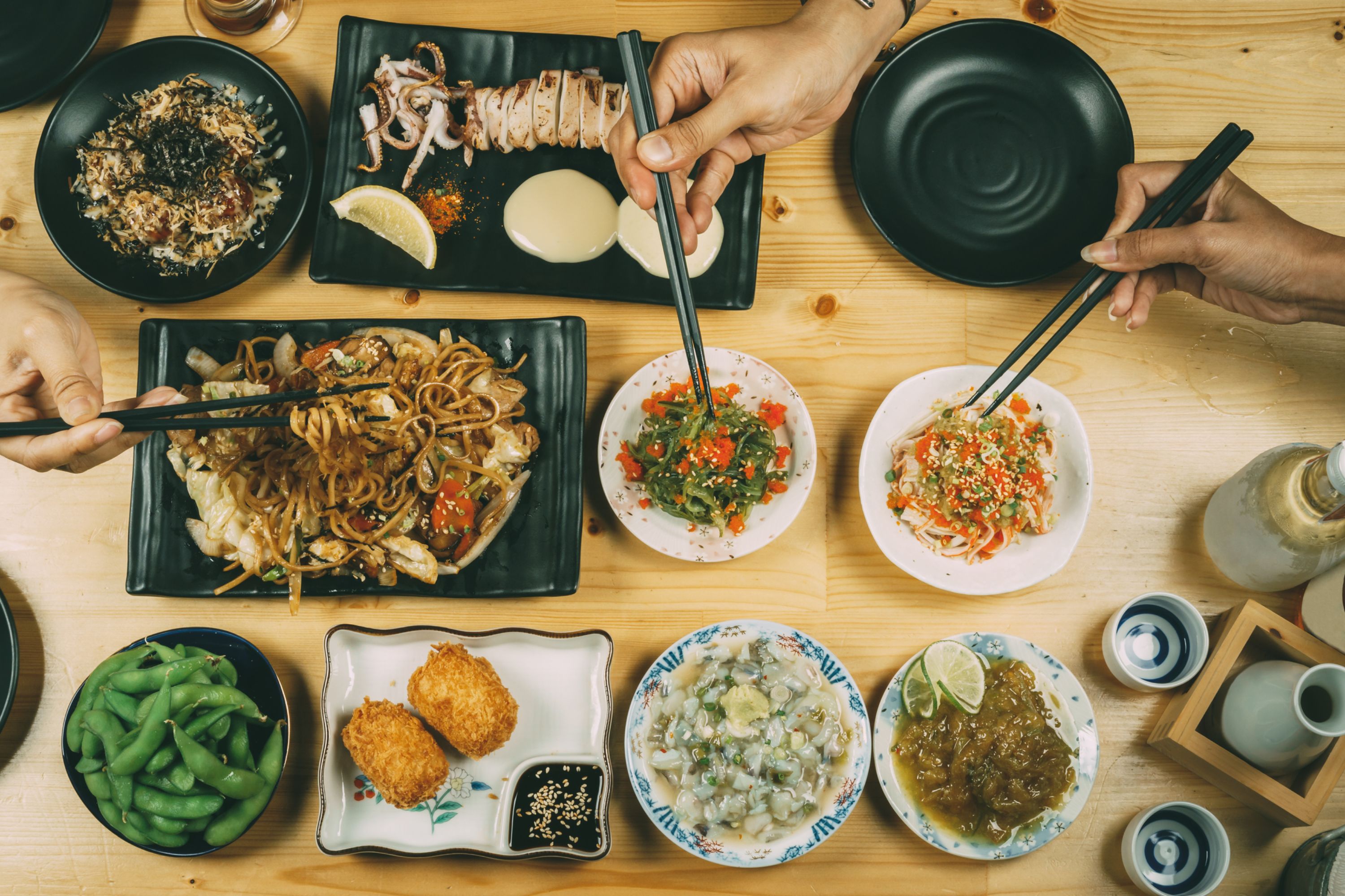 Plates of noodles, vegetables and other dishes laid out on a table. Typical food of Thailand.