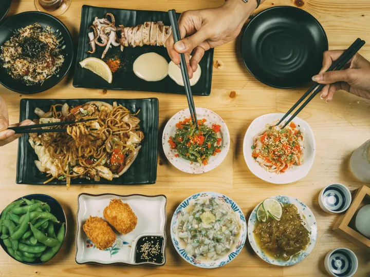 Plates of noodles, vegetables and other dishes laid out on a table. Typical food of Thailand.