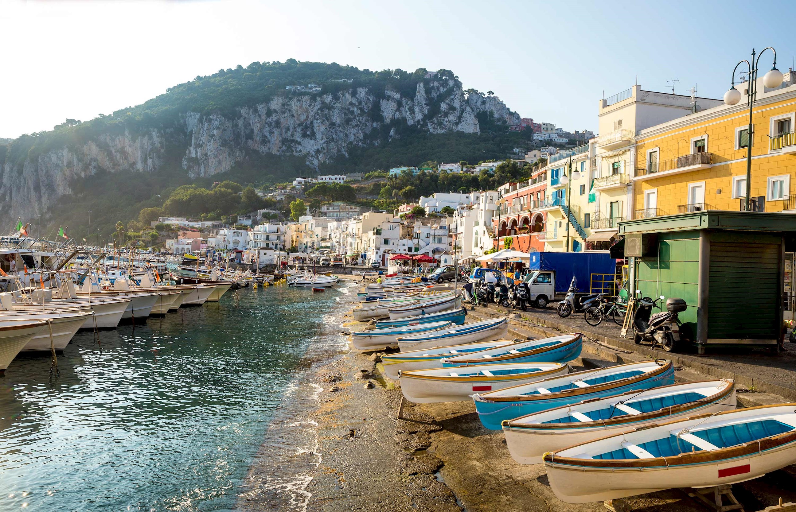 External view of a coastal harbour with small boats and colourful buildings in Naples, Italy