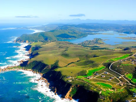 An aerial view of Knysna in South Africa showing rolling green country with a dramatic coastline.