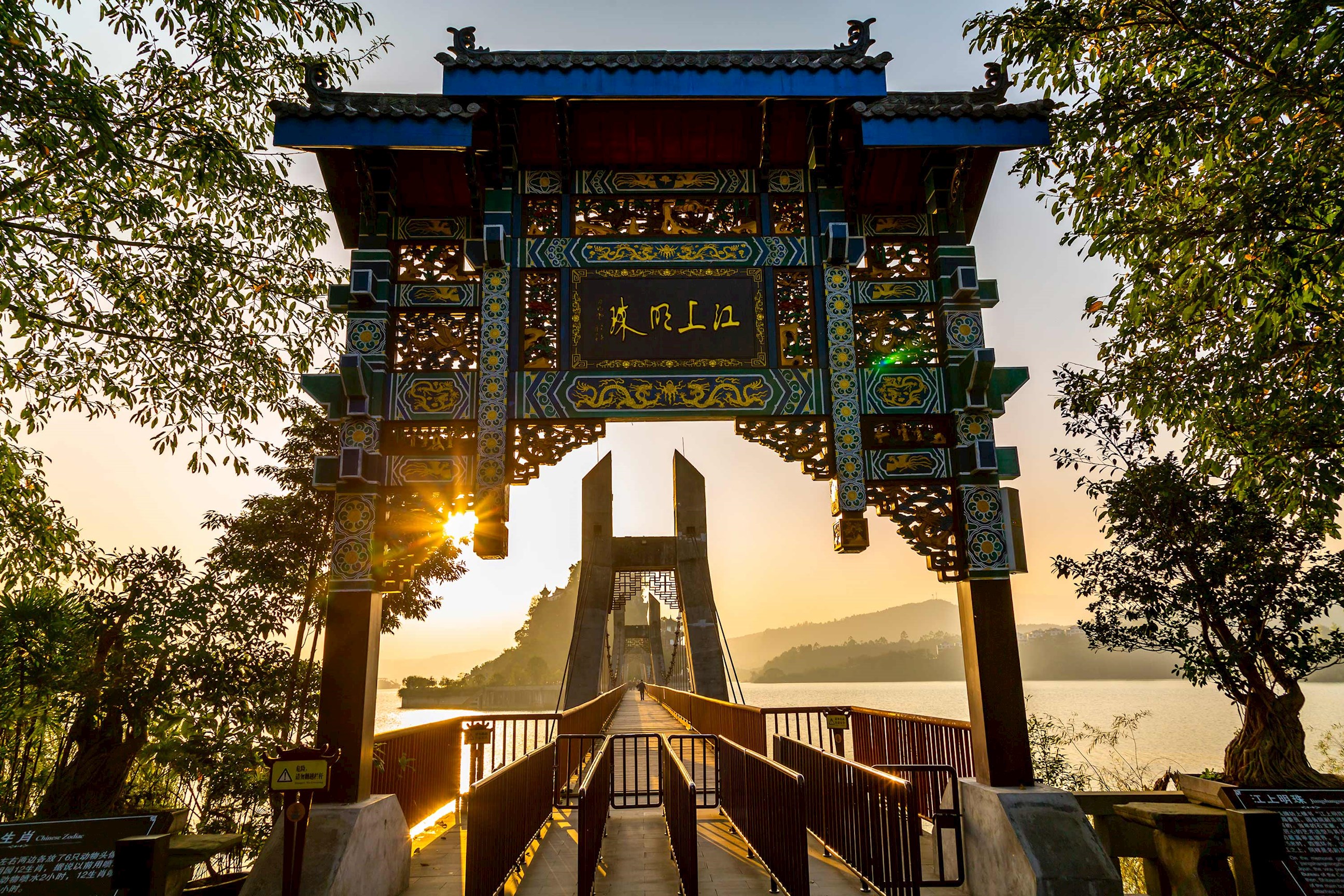 Shi Baozhai Pagoda entrance with ornate gate and suspension bridge over Yangtze River at sunset