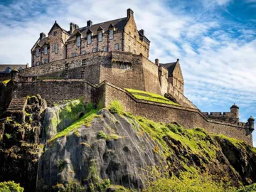 Historic castle perched on rocky hill under partly cloudy sky in Edinburgh, Scotland