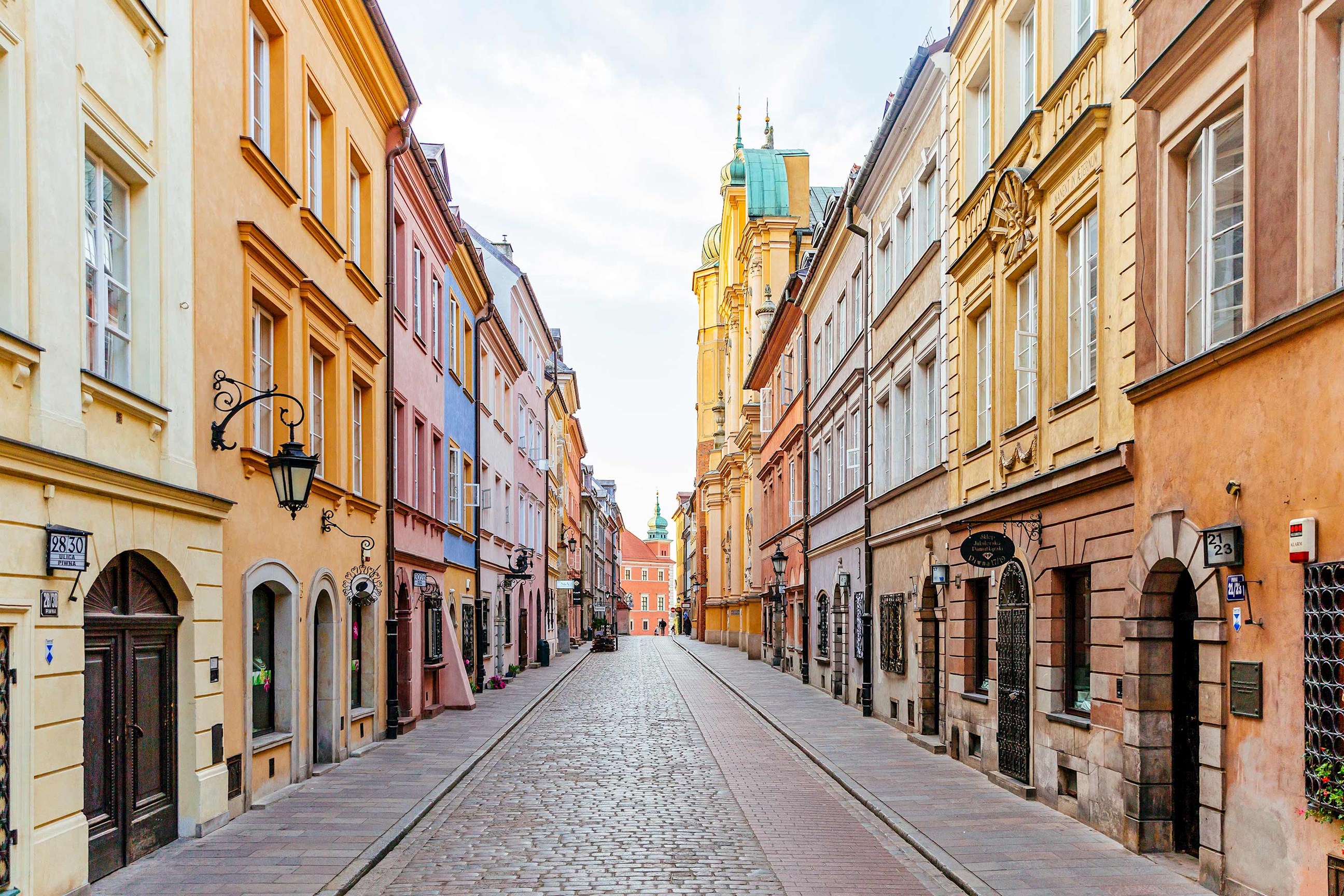 A cobblestone narrow street surrounded by colourful buildings in Warsaw, Poland