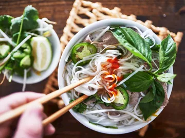 Noodle soup topped with herbs and lime