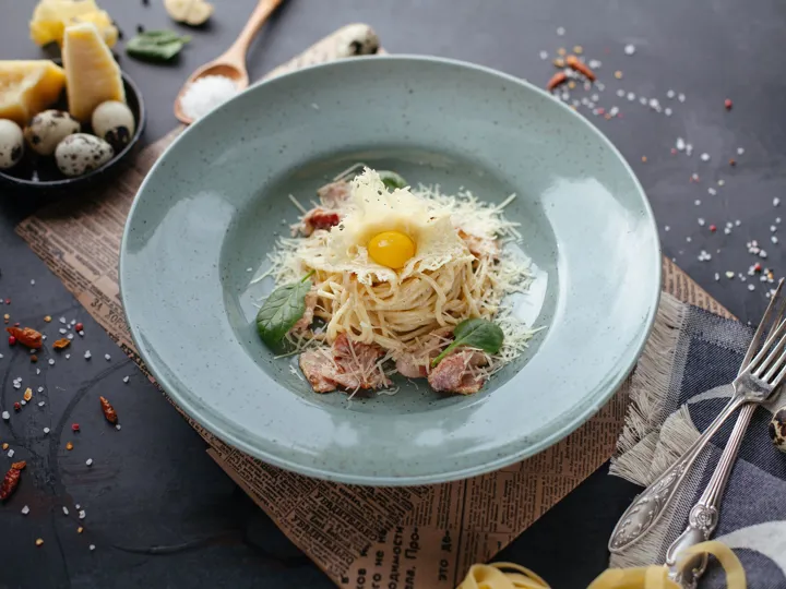 A smart bowl of pasta with ham and cheese and an egg on top, a traditional carbonara from Italy