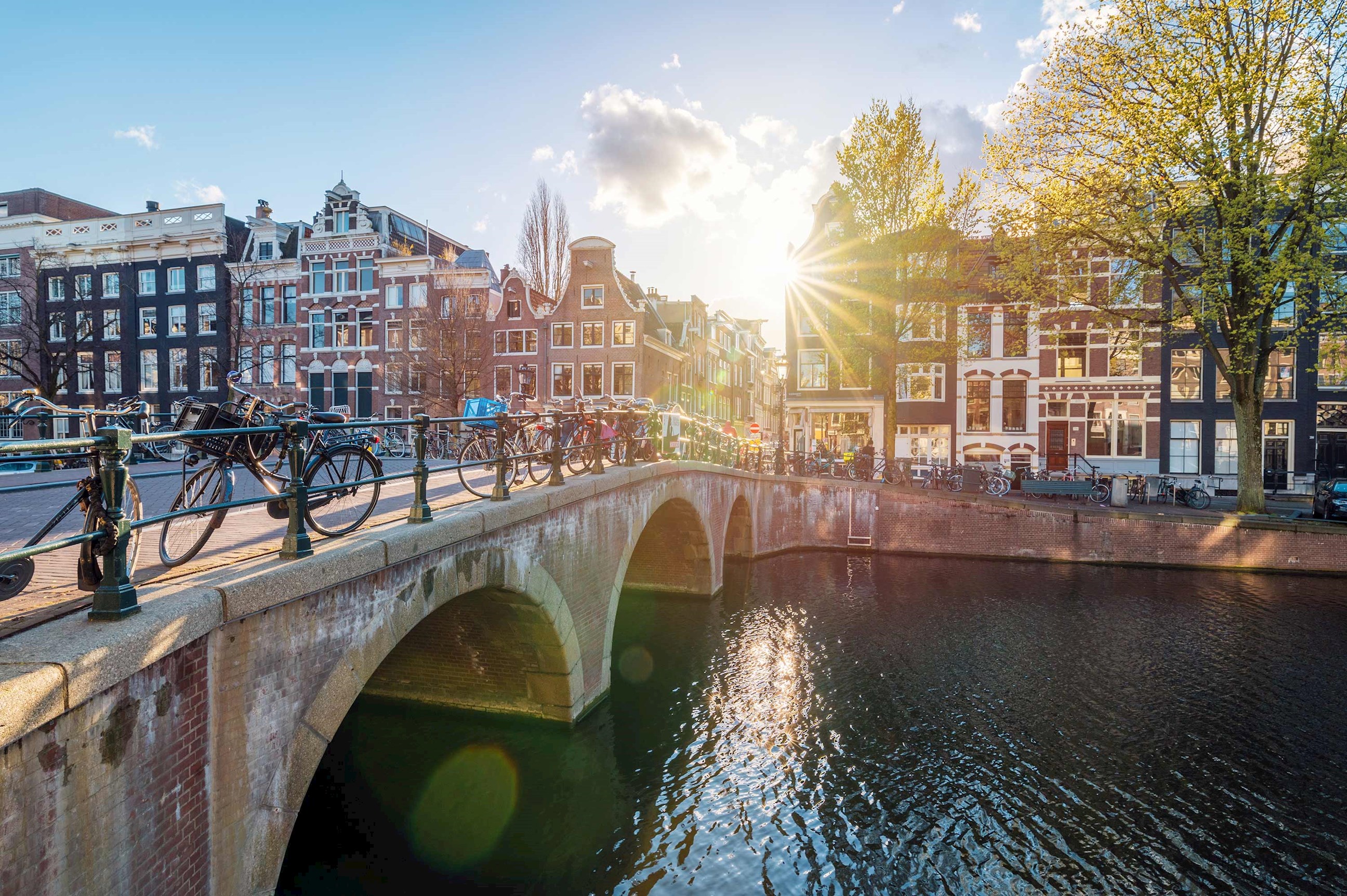 Arched bridge over canal with traditional buildings at sunset in Amsterdam, Netherlands