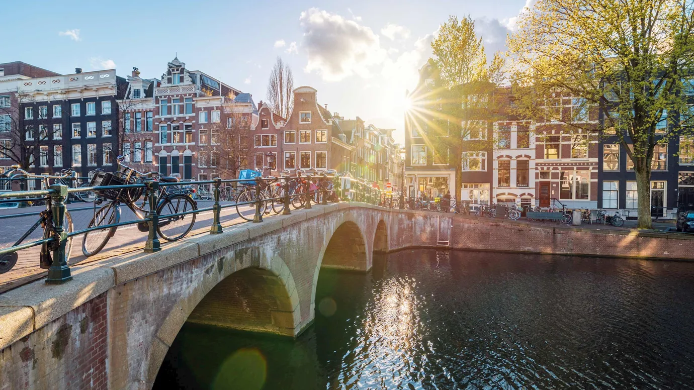Arched bridge over canal with traditional buildings at sunset in Amsterdam, Netherlands