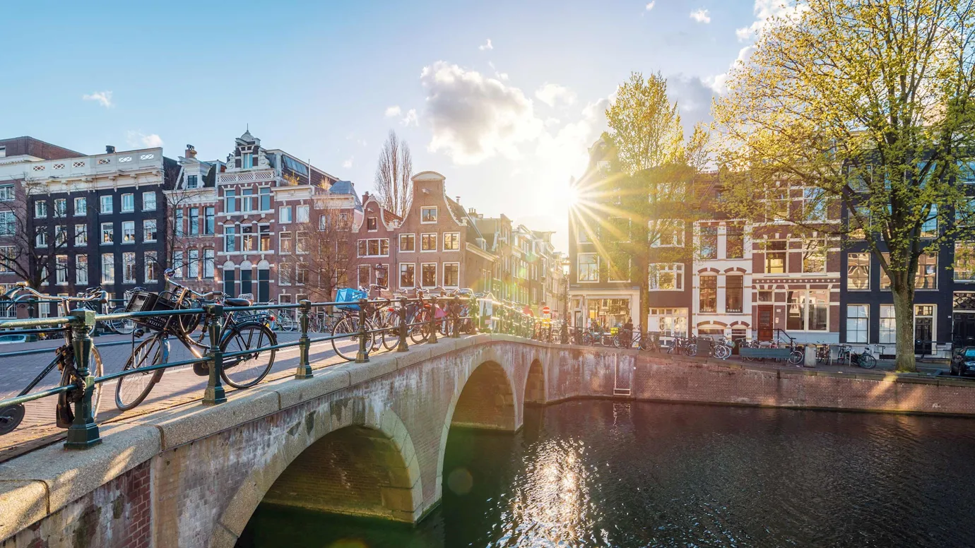 Arched bridge over canal with traditional buildings at sunset in Amsterdam, Netherlands