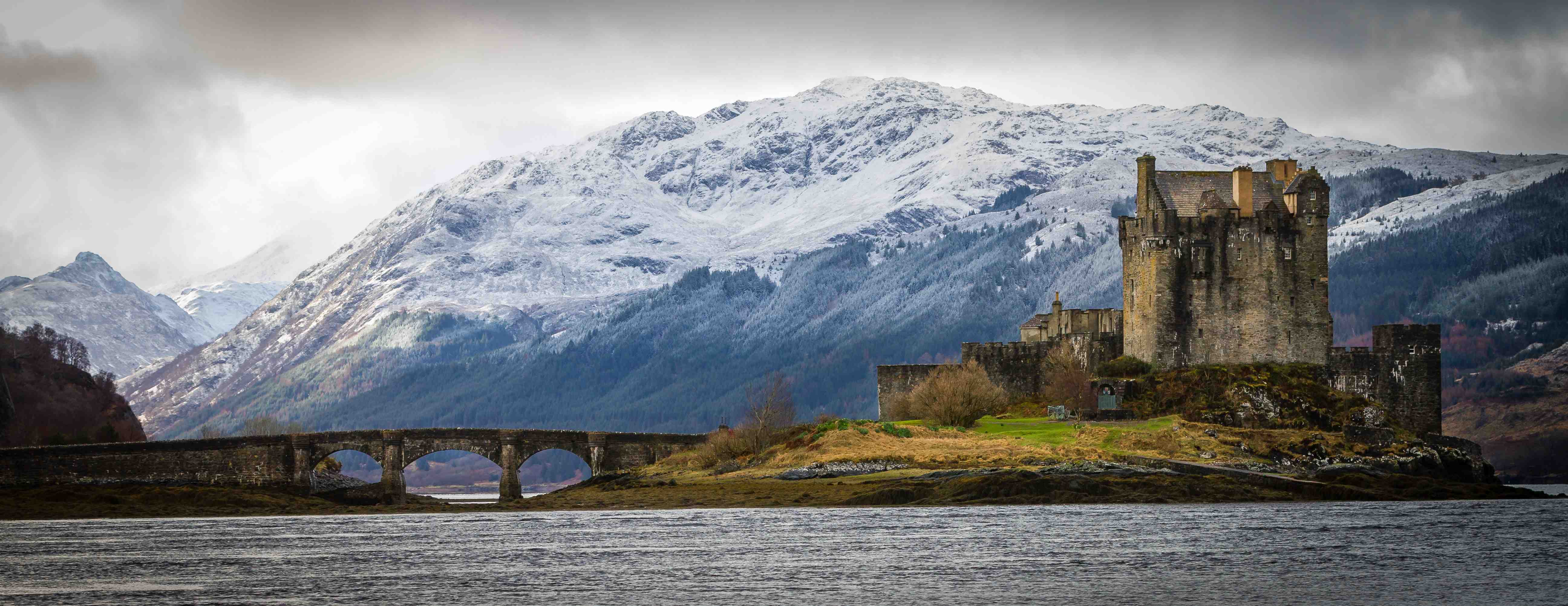 Wide shot of the Castle of Eilean Donan in front of mountain