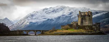 Wide shot of the Castle of Eilean Donan in front of mountain