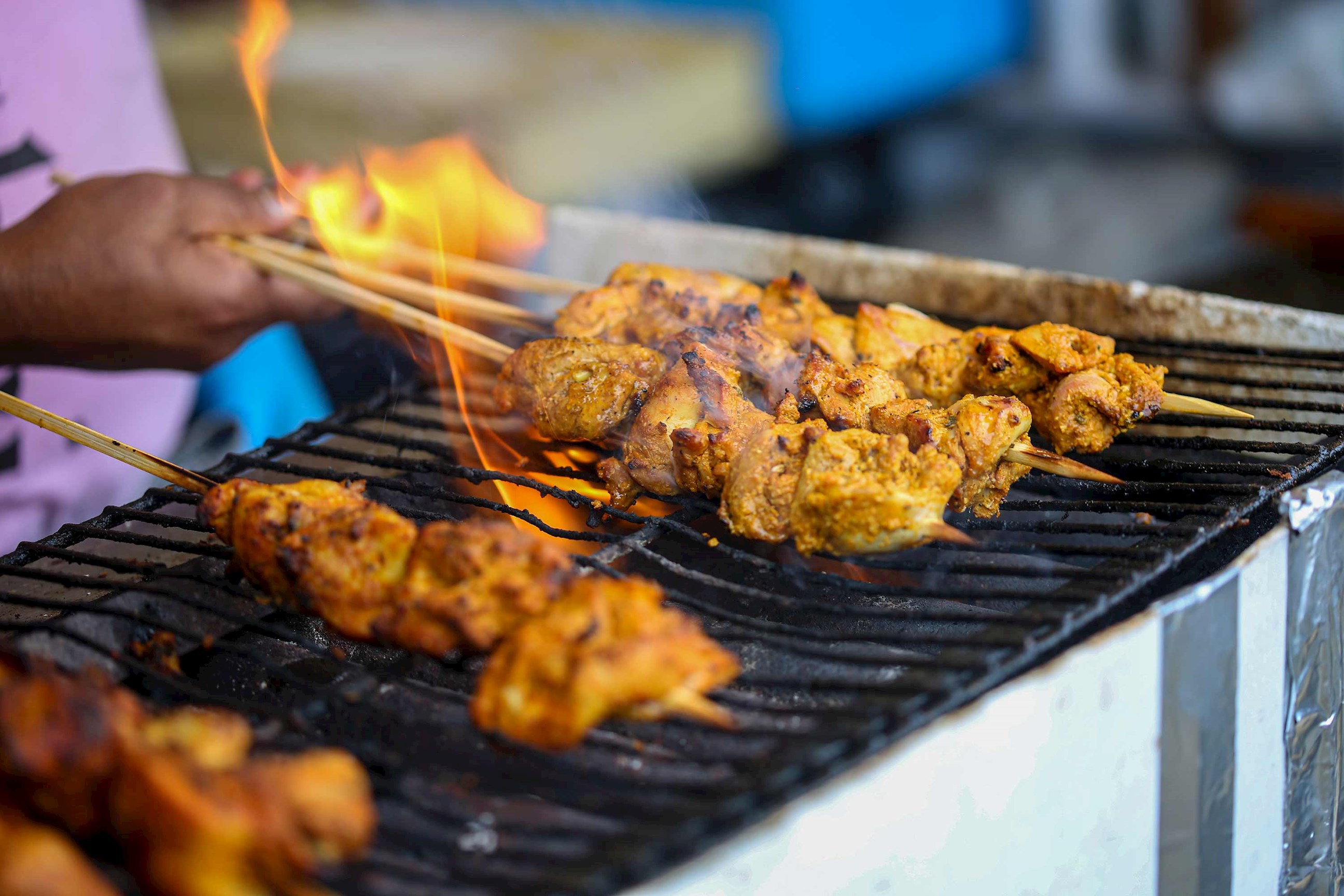 Close-up of chicken skewers grilling over open flame 