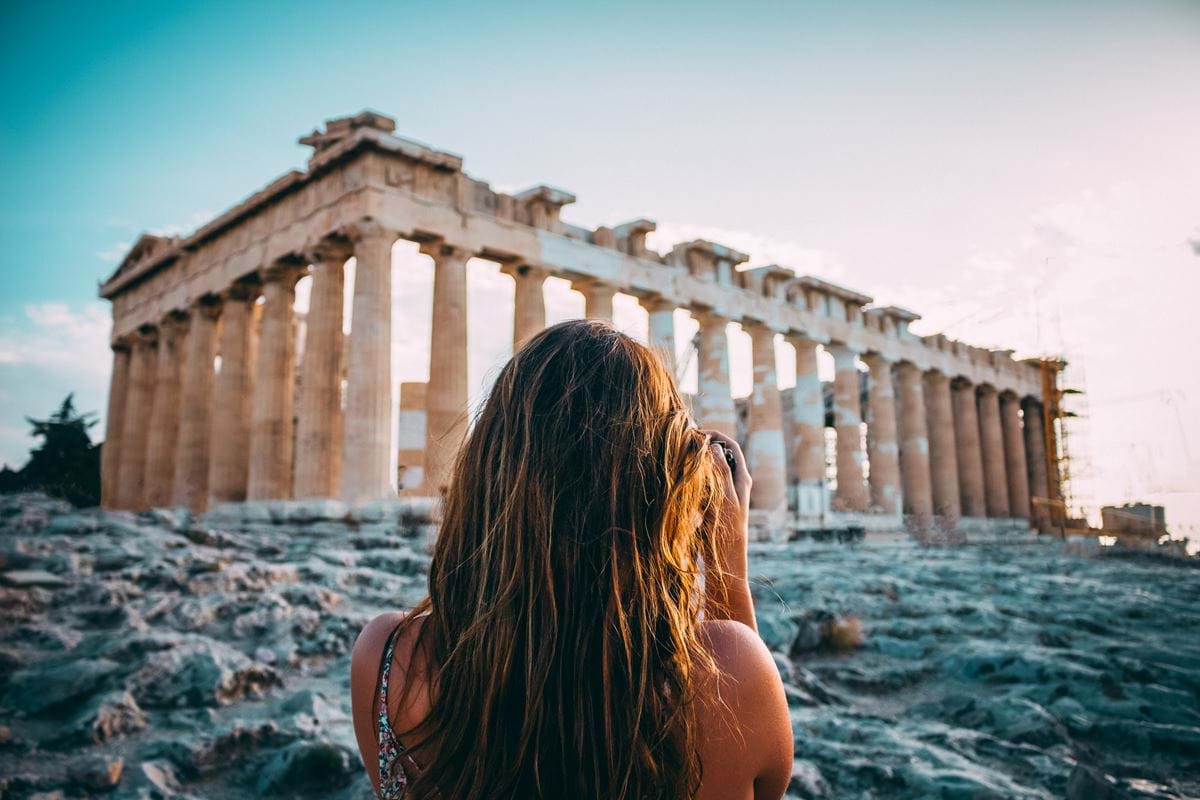 A woman standing in front of the Parthenon in Athens, Greece