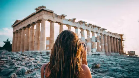 A woman standing in front of the Parthenon in Athens, Greece